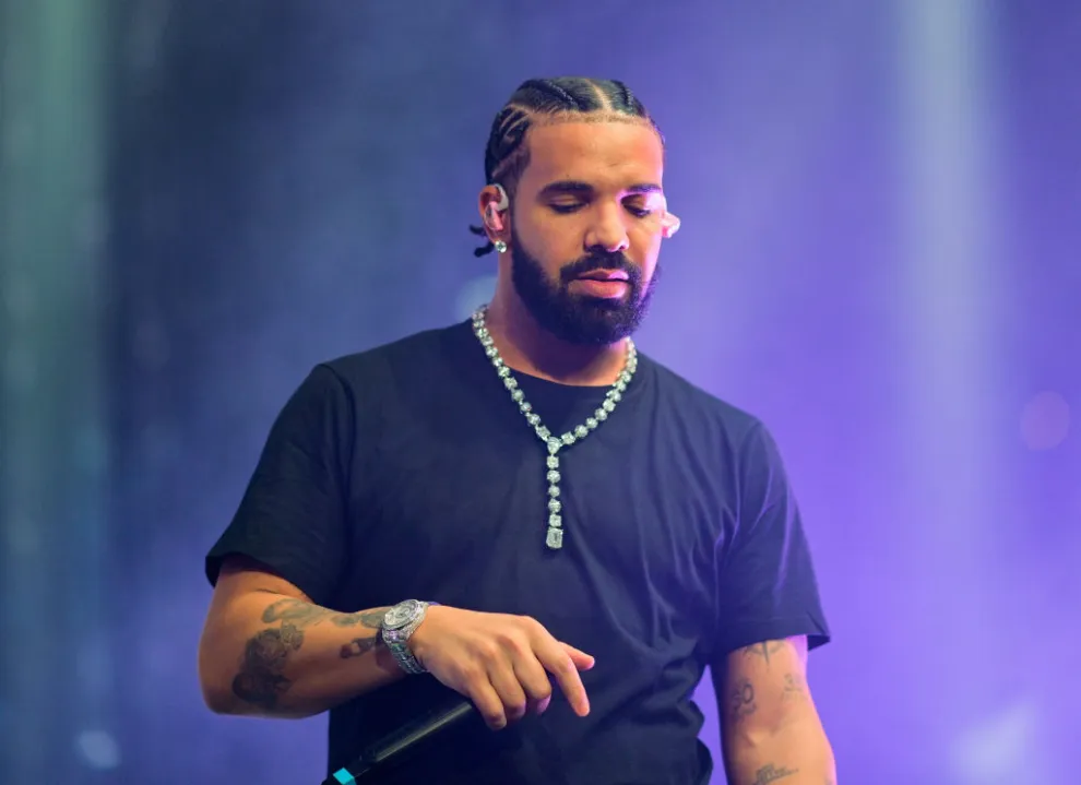 Drake performing on stage under purple lighting